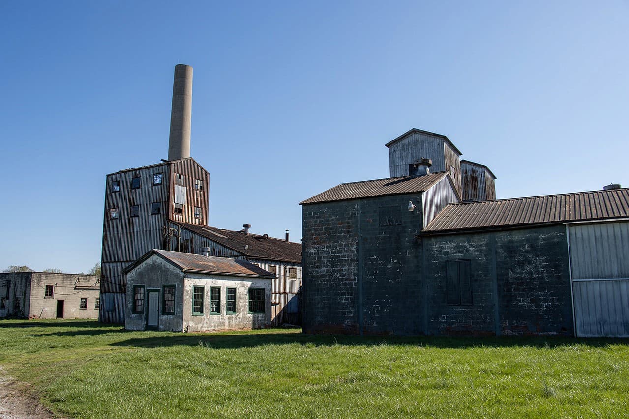 The historic distillery buildings and smokestack in Coxs Creek under a blue sky