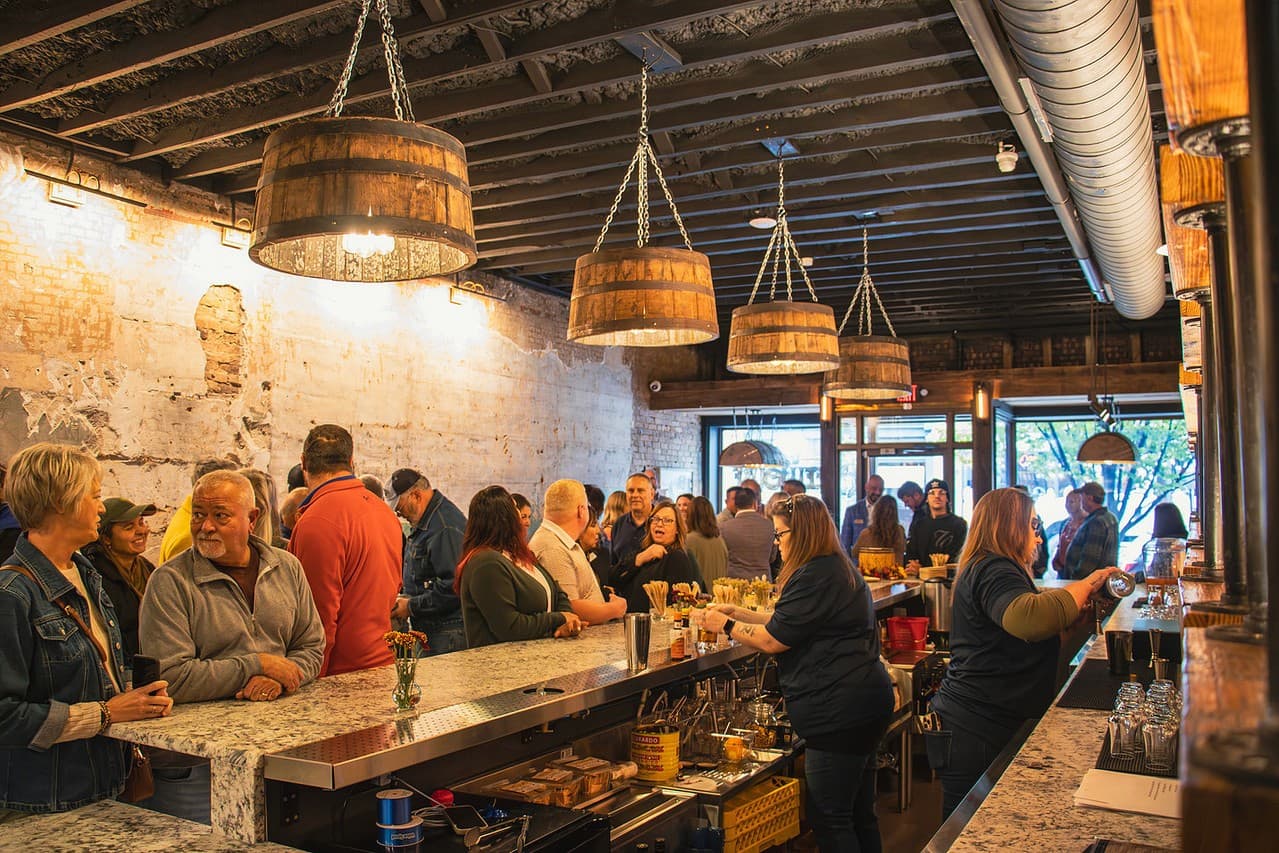 Guests filling the tasting room bar under barrel pendant lights